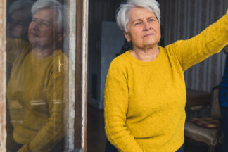darování nemovitosti, stará žena se dívá z okna