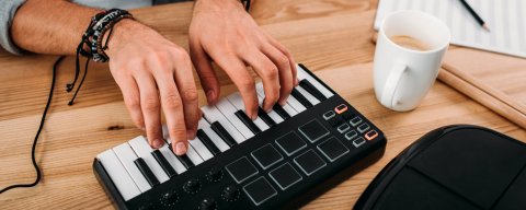 Ruce muže hrající na elektrickém pianu a vytvářející nahrávku, která je předmětem smlouvy o dílo.