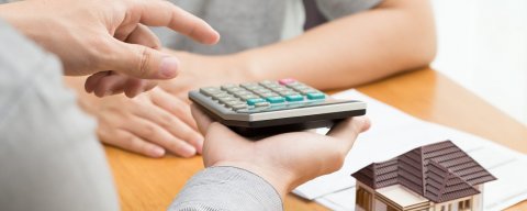 muž držící kalkulačku ukazuje druhé osobě jak počítat