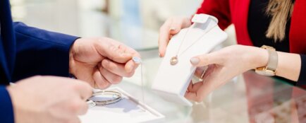 Prodavačka ukazuje zákazníkovi šperky nad prodejním pultem