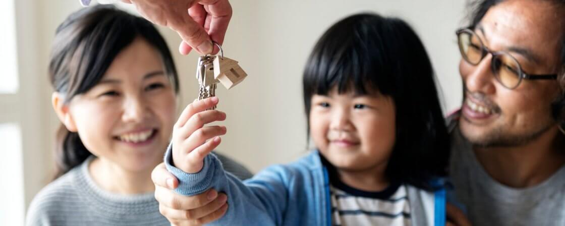 Dítě držící klíče, v pozadí její rodiče