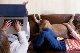 Žena pracující na počítači, vedle ní leží dítě