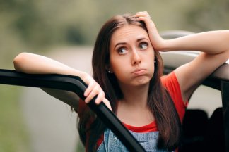 Žena stojící u auta si neví rady