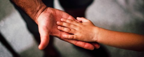 Ruce malého dítěte a otce řešícího náhradní výživné