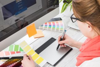 Žena sedící před počítačem zkouší barevné kombinace se vzorníkem