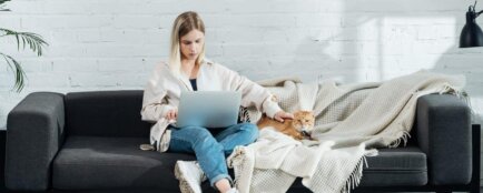 Žena sedí na svém gauči a pracuje na počítači