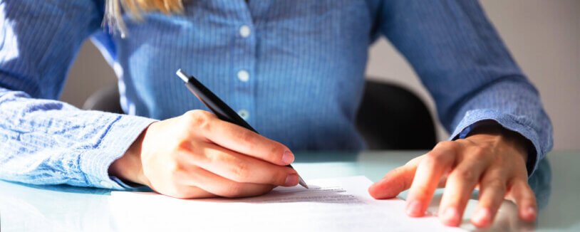 A woman signs a purchase contract for a house