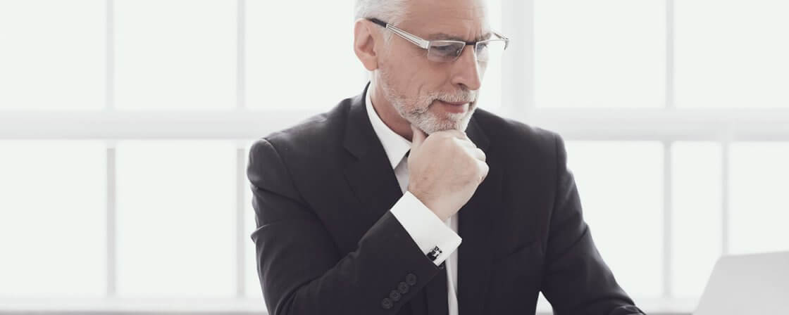 Zralý muž v obleku sedící za počítačem