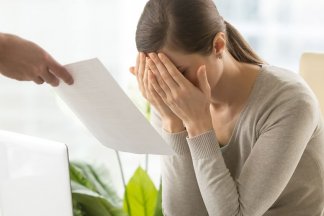 Zdrcená žena sedící u počítače dostává výpověď